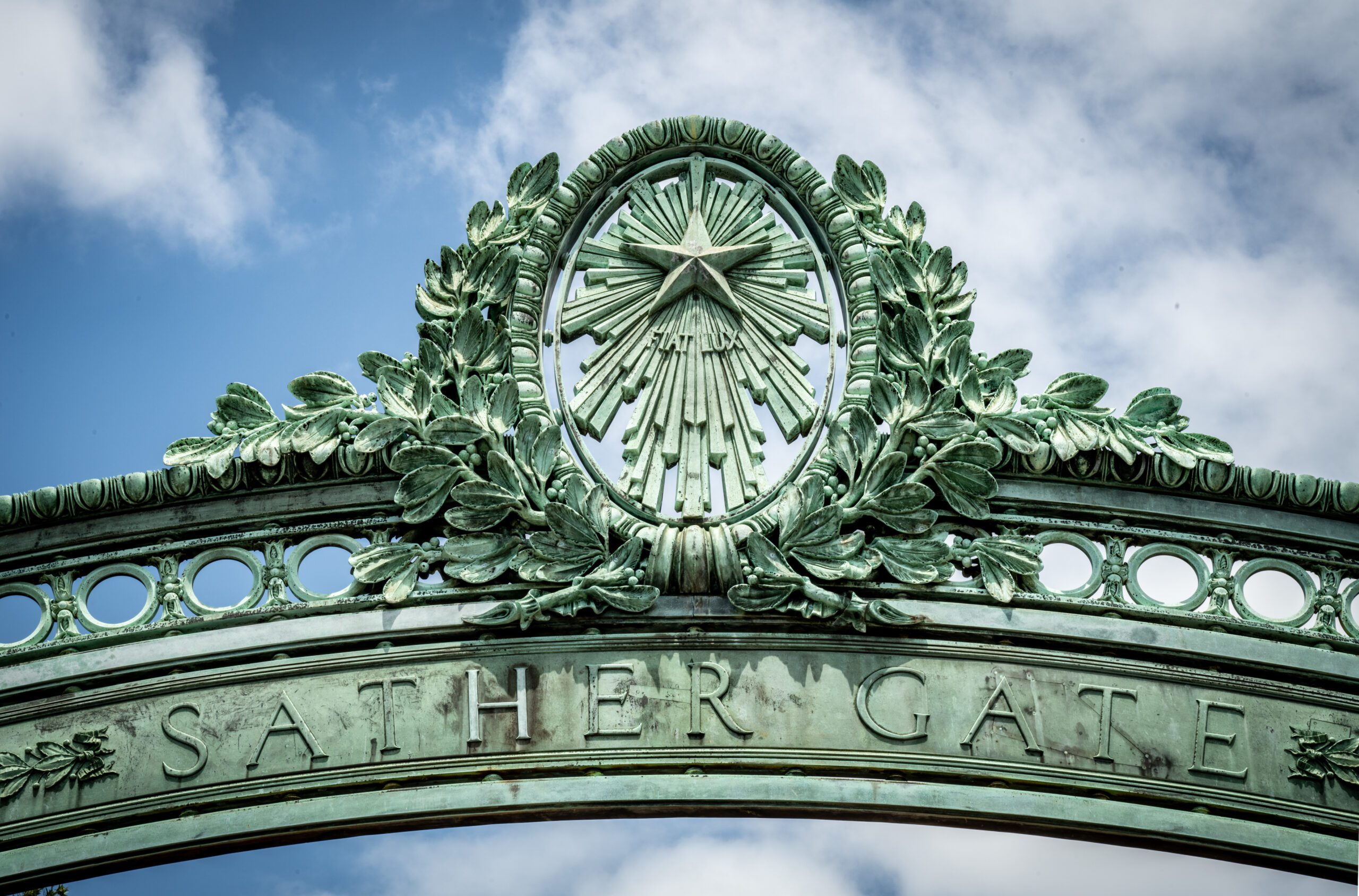 Close up of Sather Gate at day with partly cloudy sky in background.