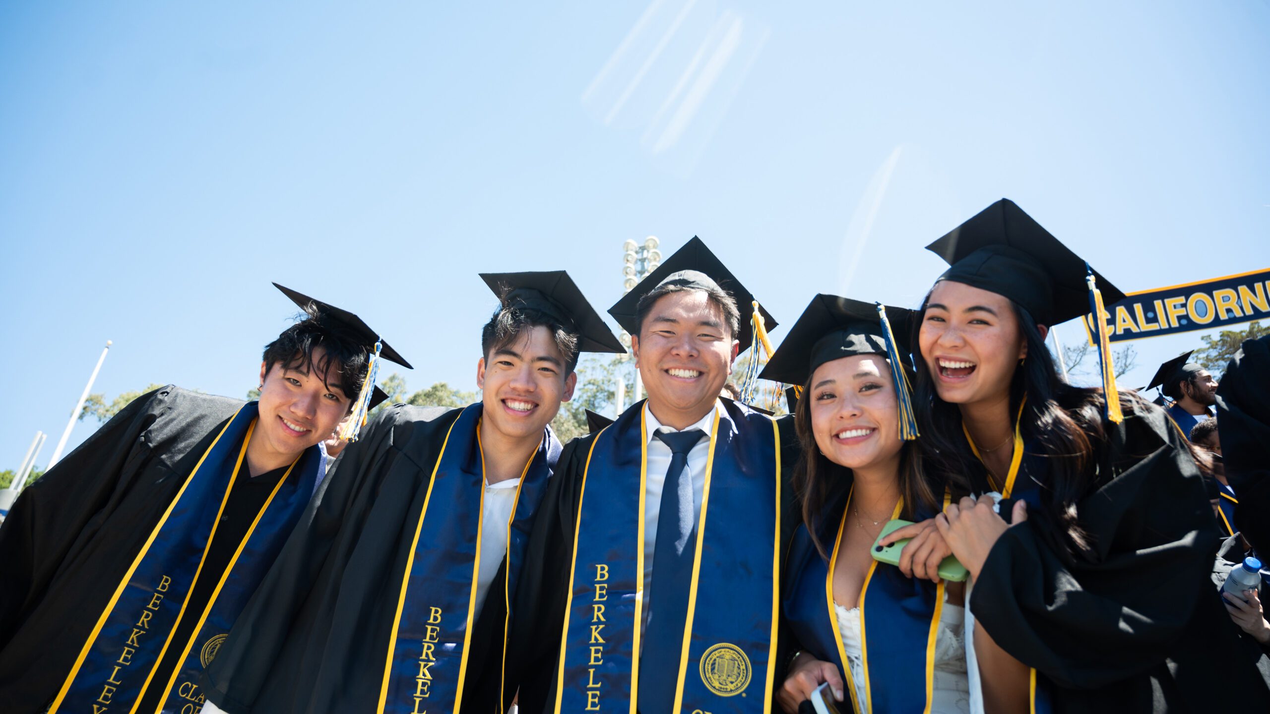 Smiling group of 5 students during Commencement wearing UC Berkeley caps and gowns