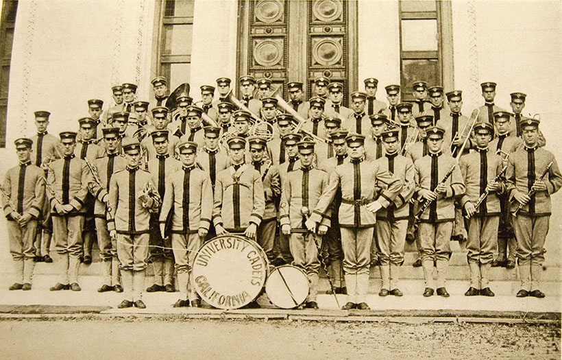 University Cadet band group photo on building steps with members holding their instruments, black and white.